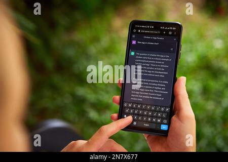February 5, 2023, Mirissa, Sri Lanka. Using OpenAI chatGPT on phone. Woman chats with artificial intelligence. Person tests neural network language Stock Photo
