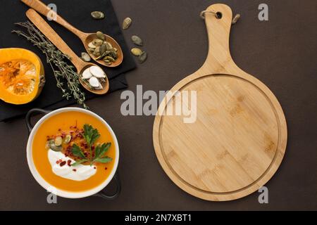 flat lay of winter squash soup in bowl with chopping board and spoons Stock Photo