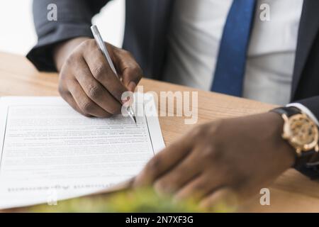 crop ethnic businessman signing papers Stock Photo