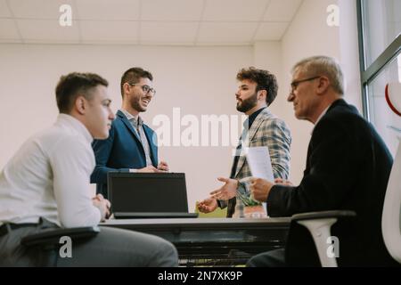 Four businessmen sharing their ideas and discussing about their upcoming project at the office Stock Photo