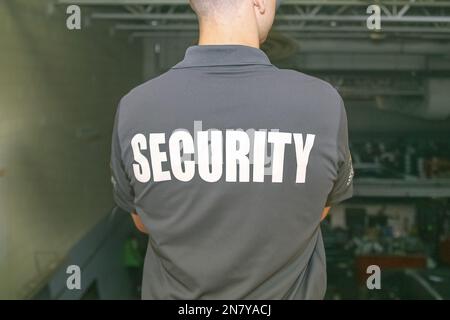 A back of a security guard patrolling inside a warehouse at night. Stock Photo