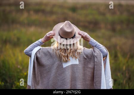 Woman wearing poncho and cowboy hat outdoors. Boho fashion style Stock Photo