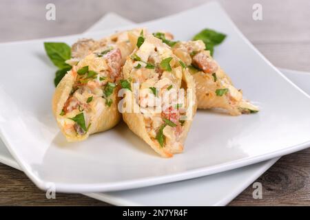 Pasta Conchiglioni stuffed with tender chicken pieces, mushrooms and vegetables in a rich creamy sauce. Stock Photo