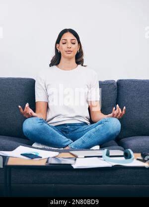 Zen, meditation and Indian woman in a living room with yoga to relax from book learning. Sofa, home and female student meditate on a couch doing Stock Photo