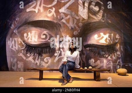 Dhaka, Dhaka, Bangladesh. 11th Feb, 2023. A woman poses in front of an artwork - ''Reetu'' - by Bishwajit Goswami during Dhaka Art Summit at National Art Gallery in Dhaka, Bangladesh. Written in Bengali across the face, the word - ''Reetu'', meaning ''˜seasons', is also a commonly used first name for Bengali girls, culturally and symbolically related to the name ''˜Bonna' (Flood) which is the theme of Dhaka Art Summit. Bangladesh has six seasons (and some would argue 'had'' as climate change has made two seasons difficult to recognize anymore) each harkening to a particular mood, fee Stock Photo