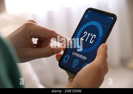 Man using smartphone to control heating system in house, closeup Stock Photo