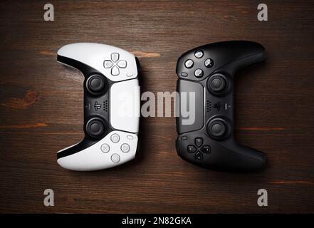 Minsk, Belarus - January 25, 2023: Two DualSense wireless controllers on wood table background. Flat lay. Stock Photo
