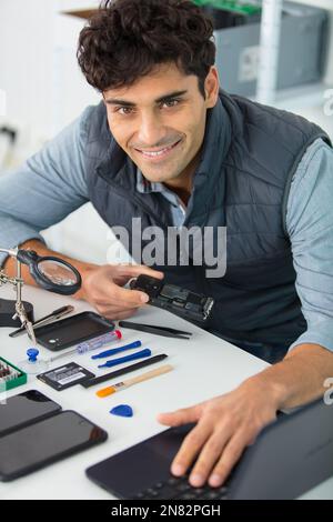 young energetic male tech or engineer repairs electronic equipment Stock Photo