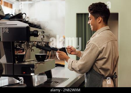 Side view of a barista using a coffee machine. Coffee shop owner preparing coffee. Stock Photo