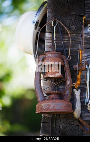 Old rusty kerosene lamp hangs on the corner of a house outdoors. Stock Photo