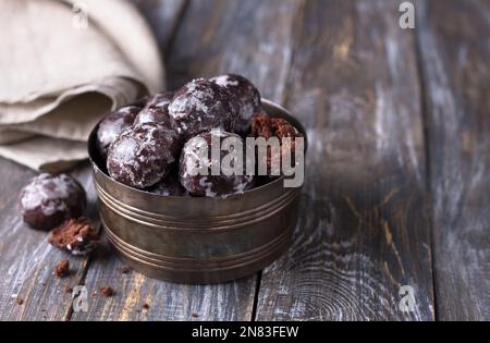 Soft vegan steamed chocolate gingerbread cookies with icing sugar in vintage bowl on wooden table, free space Stock Photo