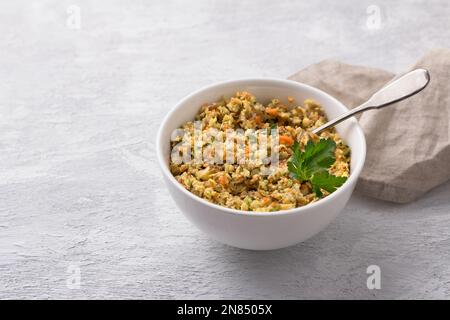Vegan lentil stuffing with vegetables for homemade dumplings, vareniki, pierogi, kreplach in white bowl on gray textured background, space Stock Photo
