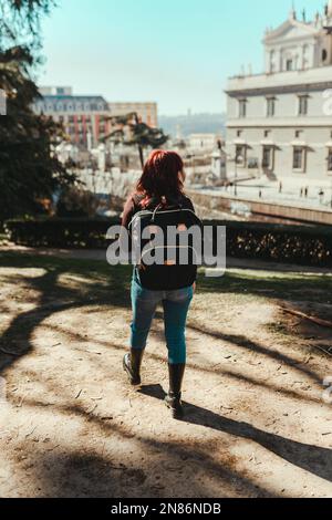 A vertical back view of a young female wearing a black backpack in a park Stock Photo