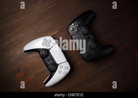 Minsk, Belarus - January 25, 2023: Black and white DualSense wireless controllers on wooden background. Flat lay. Stock Photo