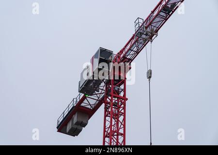 View of a construction crane cabin and part of an arrow against a gray sky. Stock Photo