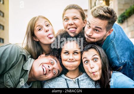 Multicultural milenial people taking selfie sticking out tongue with funny faces - Crazy life style and integration concept with interracial friends Stock Photo