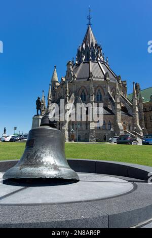 The Victoria Tower Bell, a relic from the Victoria Tower destroyed by fire in 1916, sits on a granite base in front of the Library of Parliament. Stock Photo