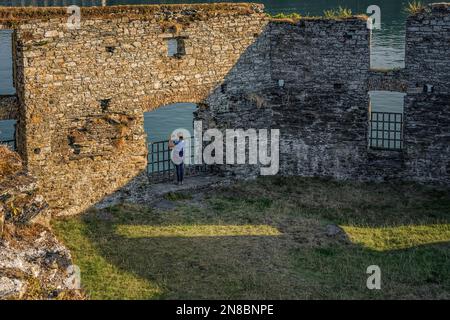 Lady hiker making photographs with her mobile phone at Ruins of James Fort Blockhouse on Castlepark peninsula. Kinsale, River Bandon, co Cork, Ireland Stock Photo