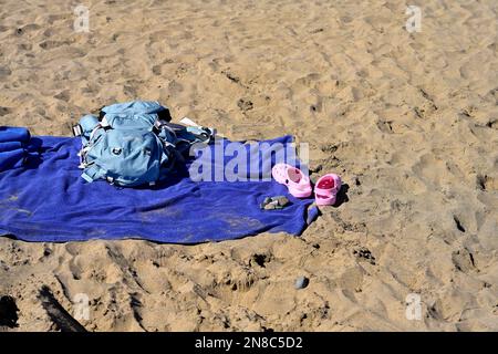 Empty beach towel, bag and shoes on sandy beach Stock Photo