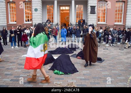 London, UK. 11th February 2023. A protester wearing an Ayatollah Khomeini mask walks around fellow protesters lying on the ground and covered in black. A group of women staged a performance in Covent Garden in protest against the Iranian regime and the executions in Iran, and in support of freedom for Iran. Credit: Vuk Valcic/17�Թ����� Live News Stock Photo
