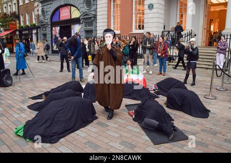 London, UK. 11th February 2023. A protester wearing an Ayatollah Khomeini mask walks around fellow protesters lying on the ground and covered in black. A group of women staged a performance in Covent Garden in protest against the Iranian regime and the executions in Iran, and in support of freedom for Iran. Credit: Vuk Valcic/17�Թ����� Live News Stock Photo