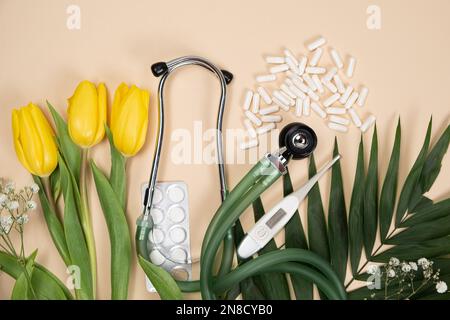 Bouquet of flowers and stethoscope on a beige background, happy doctors day, nurses week and other medical holidays. Stock Photo