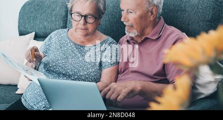 Energy gas bills cost problems in elderly lifestyle. One worried couple of senior at home using laptop to pay bills and check documents. Mature man an Stock Photo