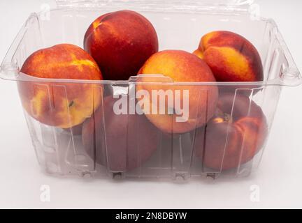 Nectarines in a plastic container on a white background. Stock Photo