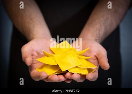 A professional chef is showing off the ravioli he made with his hands, holding them in his palms. Stock Photo