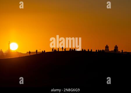 Sunset at Maspalomas Dunes - people shadows at clear sky at sunset. Black suface with yellow orange background. Stock Photo