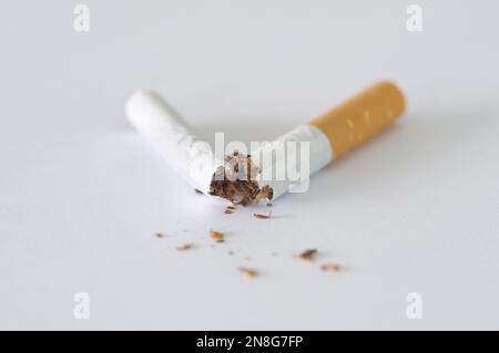 Close-up of a cigarette broken in half on a white background.  Concepts: Quit smoking, Stop smoking, Giving up smoking, Smoking addiction, Bad habits Stock Photo