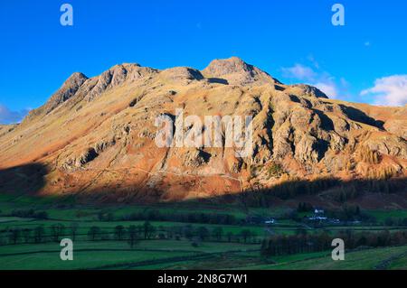 Sunlight on mountain peaks of The Langdale Pikes, rugged mountainous terrain in the Great Langdale valley, Lake District, Cumbria, England, UK Stock Photo