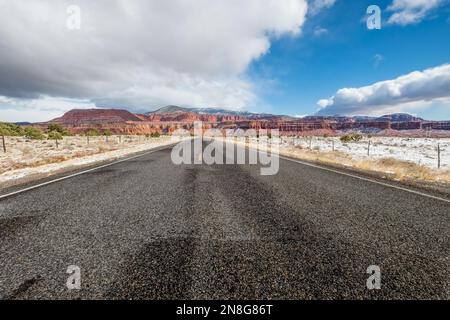 A scene of an empty asphalt highway in the middle of the semi-desert area with a background of the canyon in the daytime Stock Photo