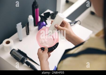 Professional hairdresser preparing dye for hair coloring in beauty salon, closeup Stock Photo