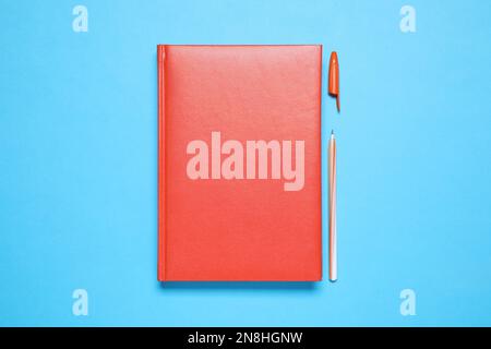 Stylish red notebook and pen on light blue background, flat lay Stock Photo