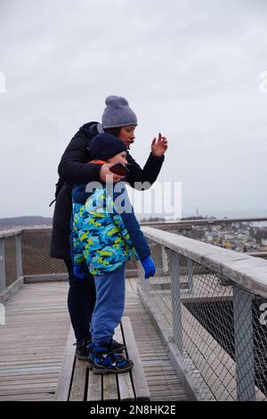 A vertical shot of Woman and child standing on a wooden tower on the Treetop Walk Usedom in Heringsdorf, Germany Stock Photo
