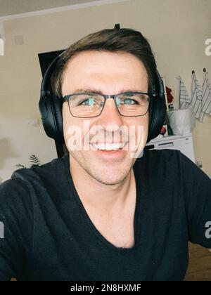 Smiling man wearing glasses and wireless headphones Stock Photo