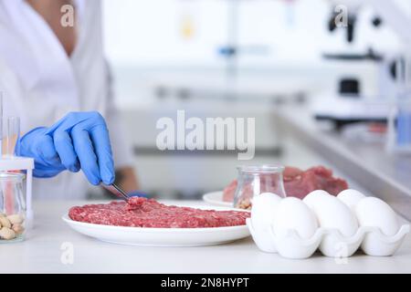 Scientist inspecting forcemeat at table in laboratory, closeup. Food quality control Stock Photo