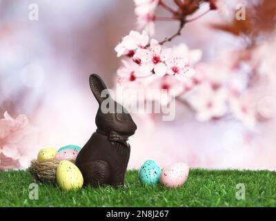 Chocolate bunny and eggs on green grass outdoors. Easter celebration Stock Photo
