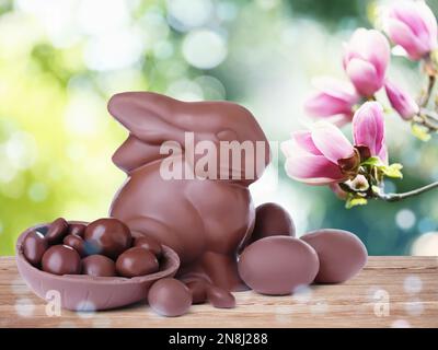 Sweet chocolate bunny and eggs on wooden table outdoors. Easter celebration Stock Photo