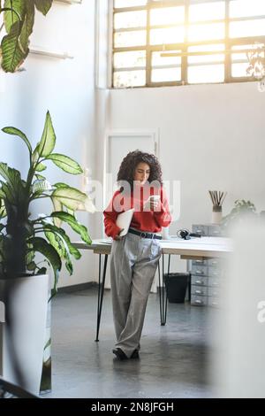 Busy young latin business woman using phone standing in office. Stock Photo