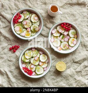 radish and cucumber salad served in three round bowls, decorated with red currants, top view Stock Photo