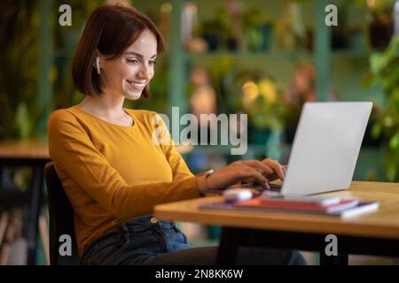 Happy brunette young woman freelancer working from cafe Stock Photo
