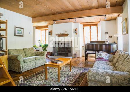 Grey and green floral patterned upholstered sofas with pine wood coffee table in living room inside old circa 1760 home. Stock Photo