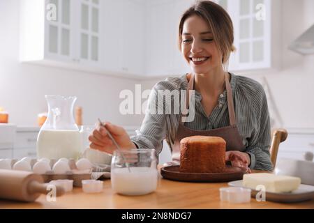 Young woman making traditional Easter cake in kitchen Stock Photo