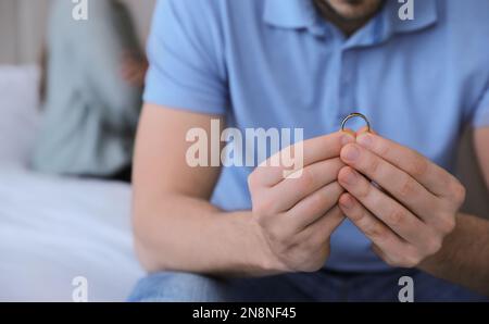 Man with wedding ring in bedroom, closeup. Couple on verge of divorce Stock Photo