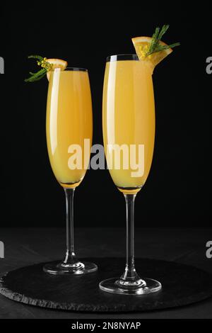 Glasses of Mimosa cocktail with garnish on black table Stock Photo