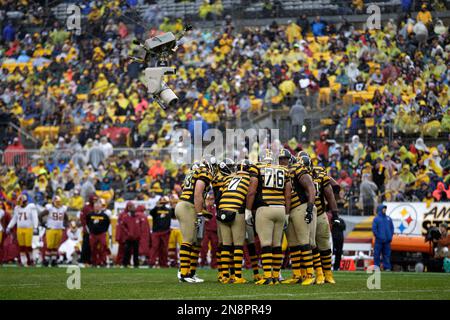 The Pittsburgh Steelers offense, wearing 1934 throwback uniforms, huddles  during the first quarter of an NFL