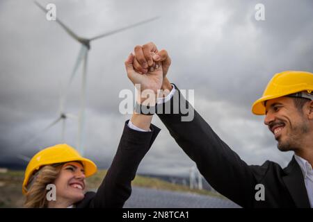 Two engineers celebrate a business success by joining hands in the sky at the photovoltaic power station. Stock Photo
