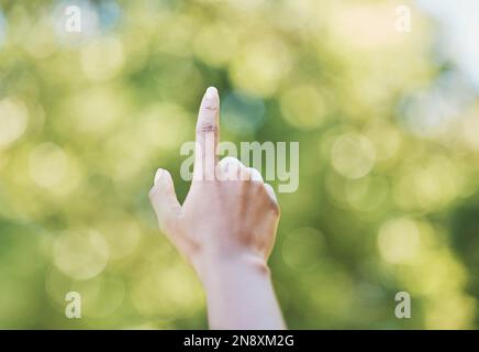 Hand, index finger and pointing in nature, outdoors or at park at something. Direction, bokeh and hands point up for gesture, signal or sign language Stock Photo